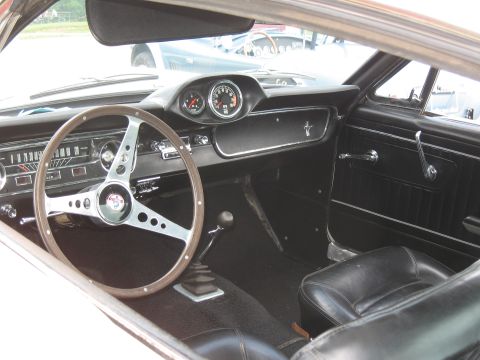 1968 Shelby GT500 - The interior of a vintage Ford Mustang, a wood-rimmed steering wheel and a manual transmission shifter.