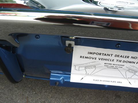 1968 Shelby GT500 - A dealer notice is attached to the lower body panel of a blue car, detailing how to remove vehicle tie-down points before customer release.