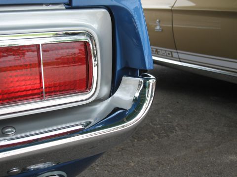 1968 Shelby GT500 - Close-up of a blue car's rear, with a gold car identified as a GT.350 in the background.
