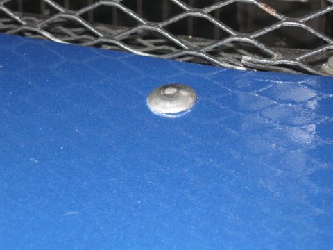 1968 Shelby GT500 - A close-up view of a blue car's hood shows a rivet and a metal grille.