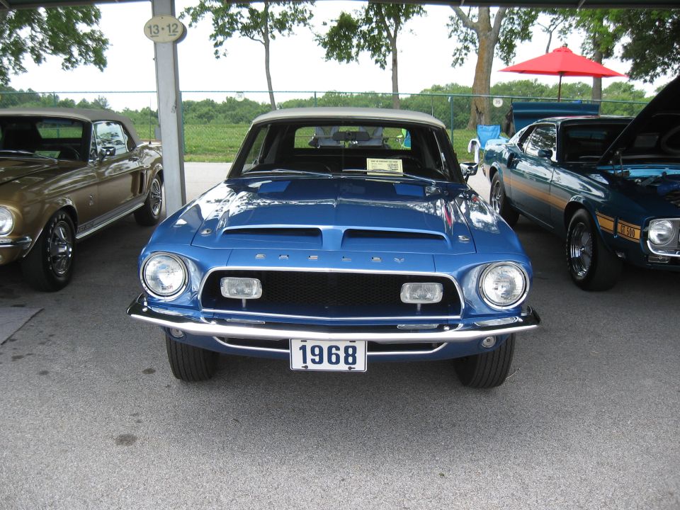Front view of a blue 1968 Shelby GT500 parked next to other classic cars