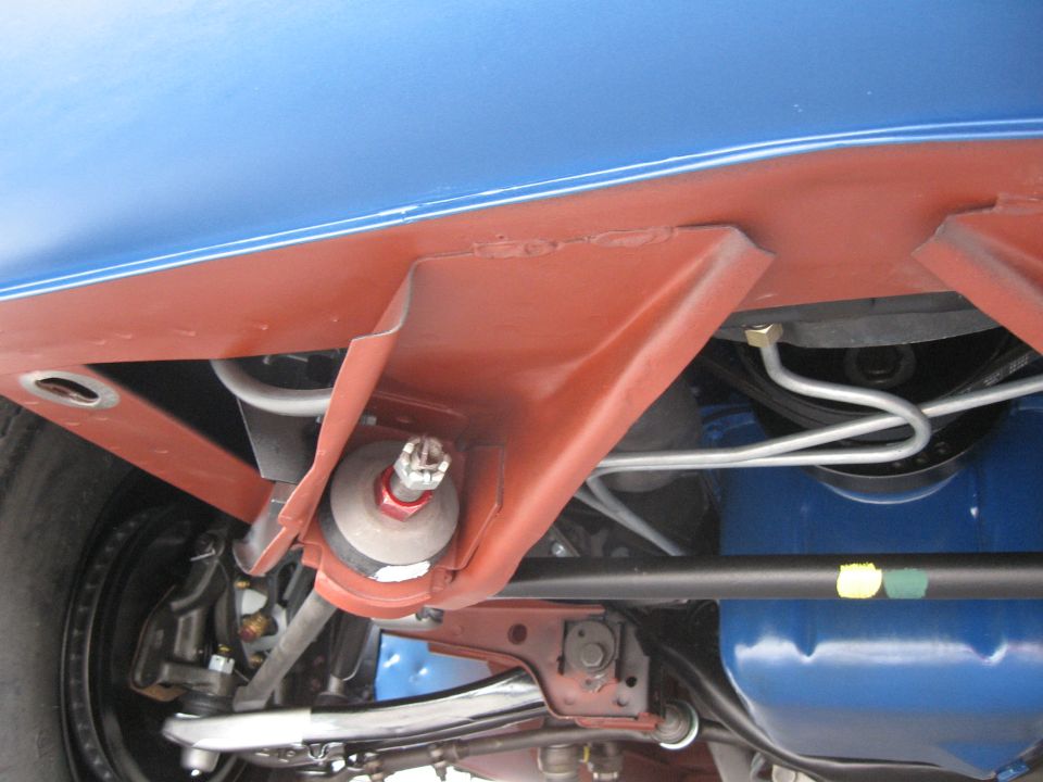 Undercarriage view of suspension parts and brake lines on a blue vehicle