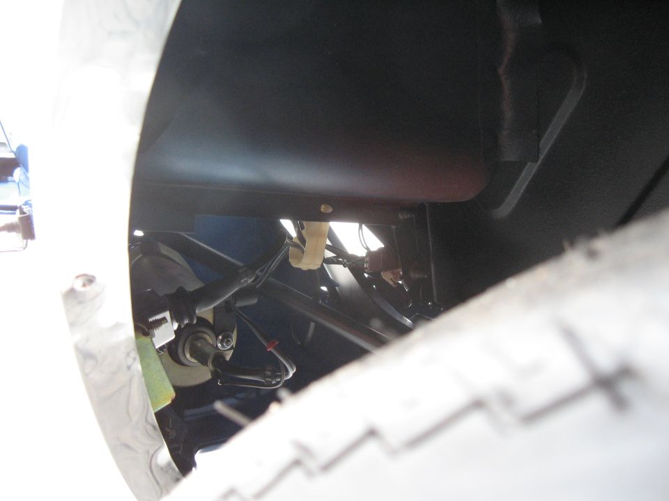 Close-up of a tire and vehicle undercarriage with visible wiring and suspension components