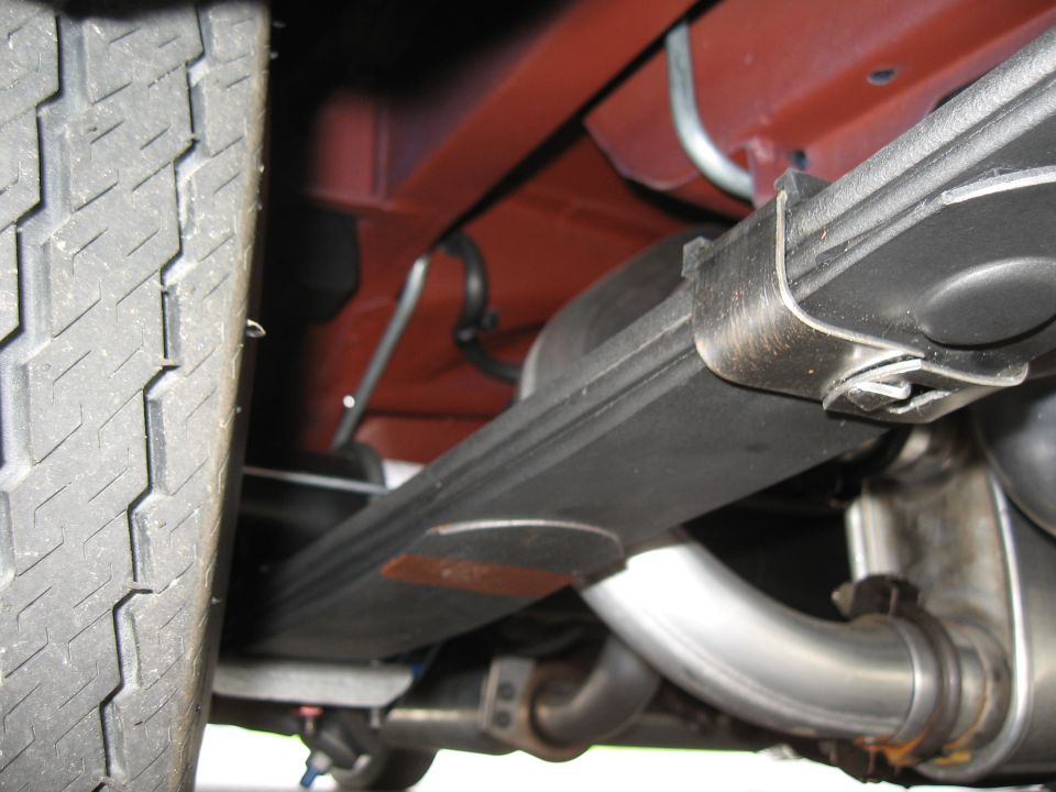 Close-up of a leaf spring and dual exhaust pipes on a vehicle's undercarriage