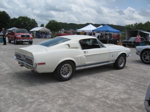 1968 Shelby GT500 - A white 1968 Shelby GT500 is parked at an outdoor event, showing its distinctive body style and racing stripes.