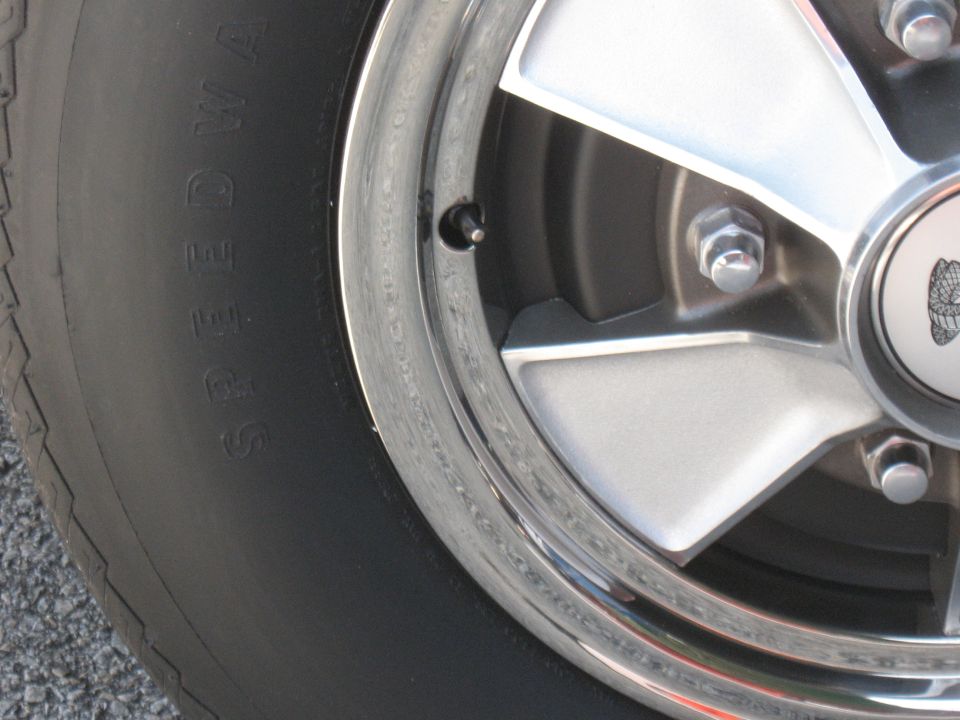 Close-up of a chrome wheel with a tire that has "SPEEDWAY" text on it