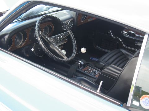 1968 Shelby GT500 - The interior of a 1969 Ford Mustang features woodgrain accents on the dashboard and console, black vinyl seats, and a distinctive white bal…