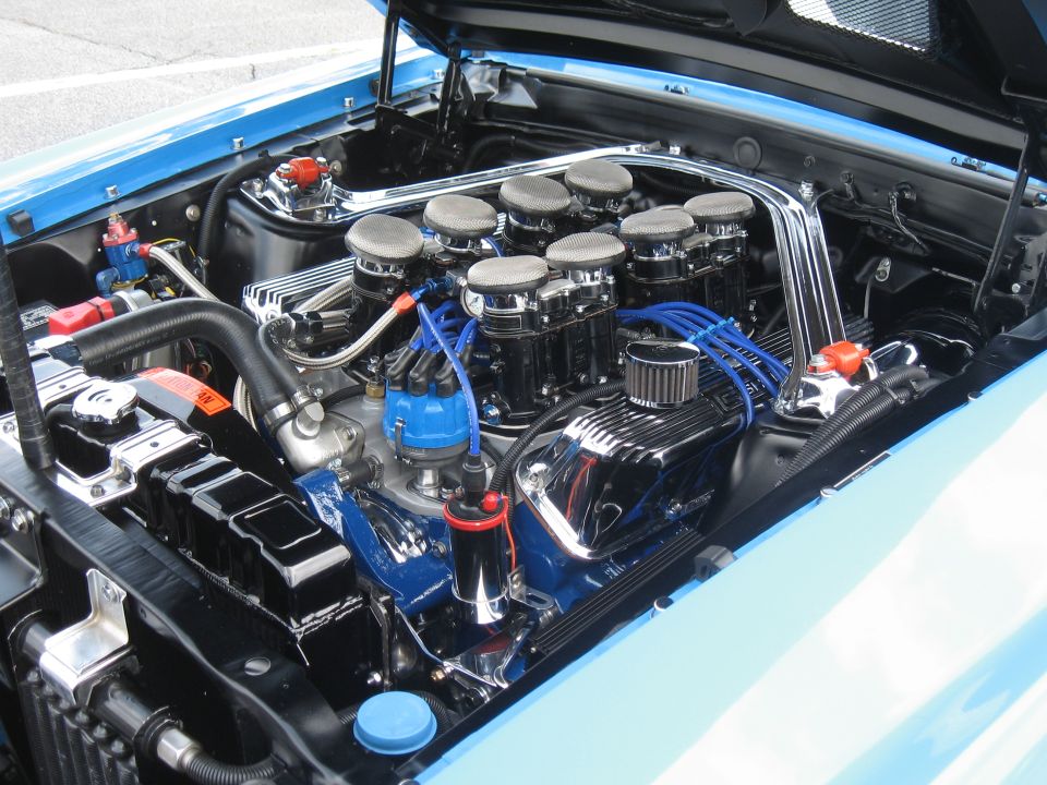 Close-up of a V8 engine with eight individual carburetors and blue spark plug wires