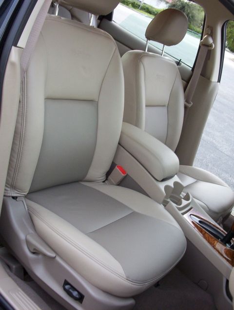 2003 Ford Taurus - Interior shot through the open passenger door of a sedan showing tan/beige leather front bucket seats with the center console armrest folde…
