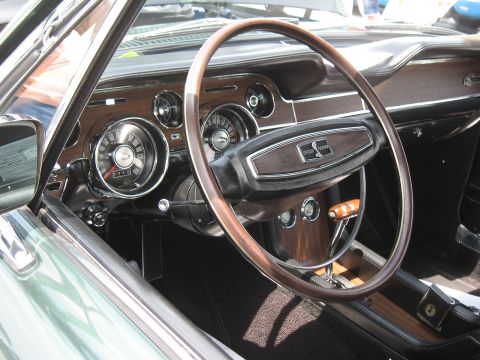 1968 Shelby GT500 - The interior of a 1968 Shelby GT500 features a wood-grain dashboard and a steering wheel with the iconic Cobra emblem.