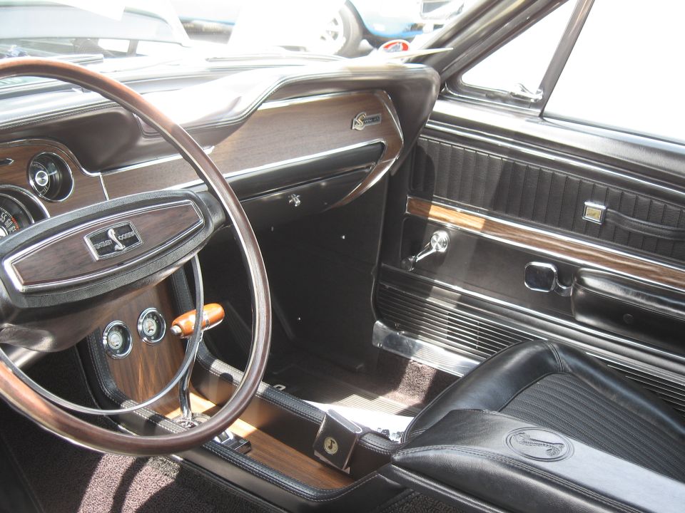 1968 Shelby GT500 interior showing woodgrain dash, steering wheel with Cobra emblem, and black seats