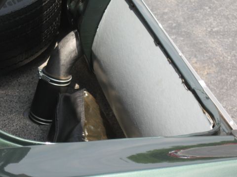 1968 Shelby GT500 - Close-up of a spare tire and exhaust pipe assembly inside a vehicle's trunk area.