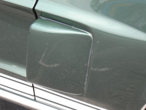 1968 Shelby GT500 - Close-up of a green car's fuel door, showing its side profile and chrome trim details.