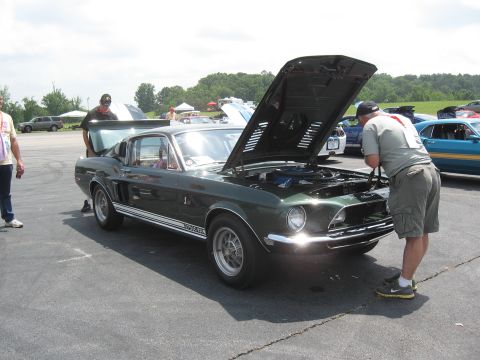 1968 Shelby GT500 - A dark green 1968 Shelby GT500 is displayed with its hood and trunk open at an outdoor car show.