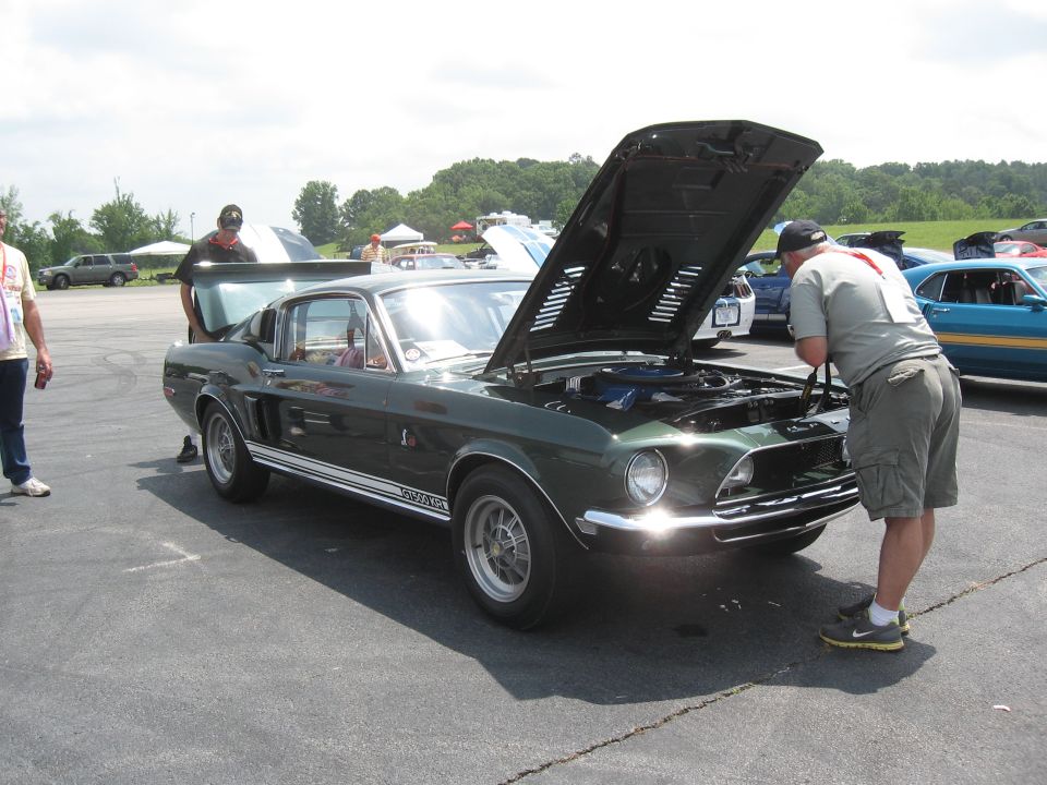 Green 1968 Shelby GT500 with hood and trunk open, people looking at it
