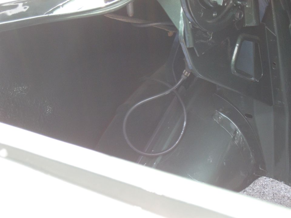Interior view of a car's trunk, showing the carpeted floor and black side panels with a coiled cable
