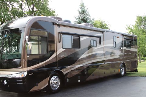 2003 Ford F-350 - This motorhome features a distinctive brown, beige, and black wavy stripe paint scheme, viewed from its side.