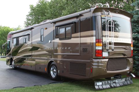 2003 Ford F-350 - This RV motorhome is parked on a paved surface with grass and trees in the background.