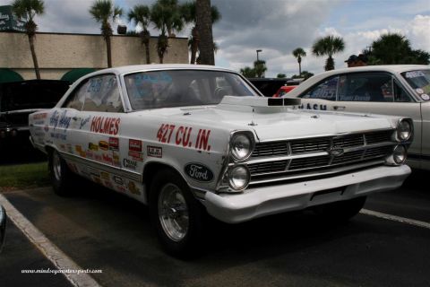 1967 Ford Fairlane - White 1966 Ford Fairlane drag car with extensive racing decals and a prominent hood scoop is parked next to another vehicle.