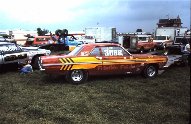 Orange and red drag coupe lettered 'Frantic Fred' number 3086, side view at a race pit