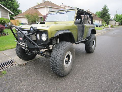 1974 Ford Bronco - This modified 1974 Ford Bronco features oversized tires, a custom bumper, and a roll cage, indicating significant off-road capability.