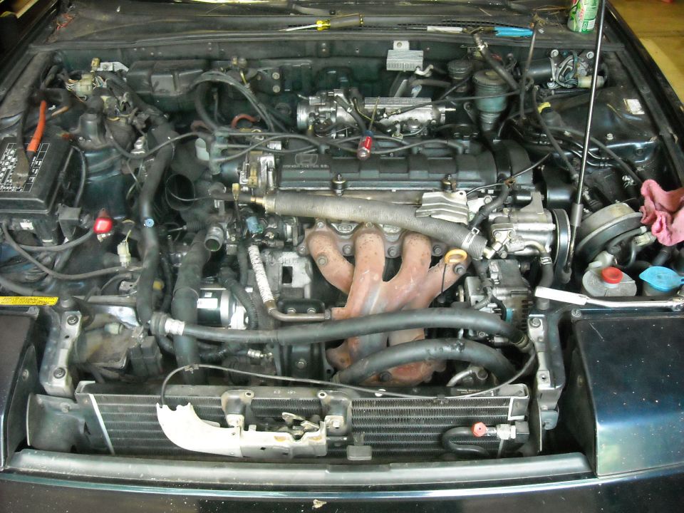 Engine bay with hoses, wires, and engine components visible