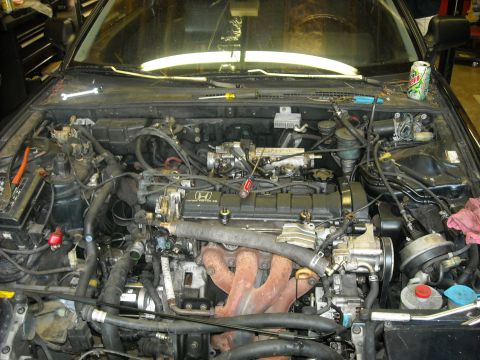 1979 Ford F-150 - The engine bay of a vehicle, showing various components and wiring, with a Honda emblem on the engine cover.