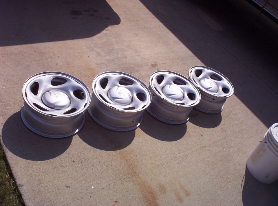 Four silver steel wheels with Toyota center caps lined up on a concrete driveway