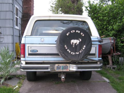 1985 Ford Bronco - The rear of a Ford Bronco is shown, a spare tire cover with the Ford Bronco logo and a license plate.