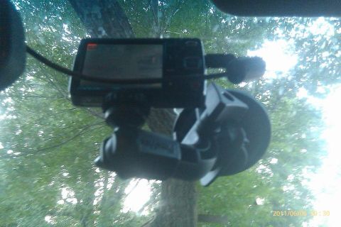 2000 Mercury Grand Marquis - A dashcam is mounted to the interior of a vehicle's windshield, with trees and sky visible through the glass.