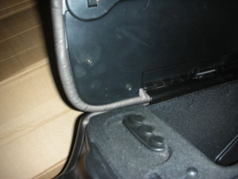 1998 Ford Crown Victoria - Close-up of the hinge and padded lid underside of a black automotive center console storage compartment.