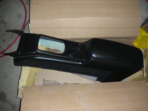 1998 Ford Crown Victoria - complete black center console with padded armrest, cupholders and a vanity mirror lying in a cardboard box.