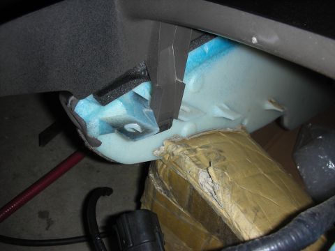 1998 Ford Crown Victoria - Underside of a center console assembly exposing blue foam padding, a mounting bracket and wiring.