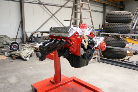 1973 Ford Ranchero - A V8 engine is displayed on a stand in a workshop, with tires and other equipment in the background.