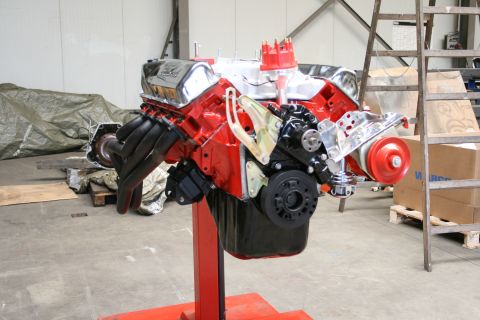 1973 Ford Ranchero - A red Ford V8 engine with chrome valve covers is displayed on a stand in a workshop.