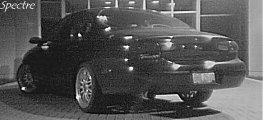 1999 Ford Taurus - Rear view of a black sedan with custom wheels, parked outdoors.