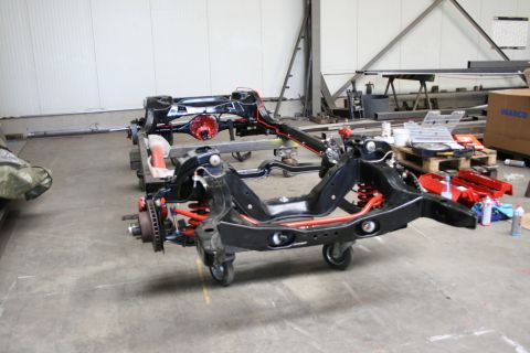 1973 Ford Ranchero - A disassembled vehicle chassis with red suspension parts sits on wheels in a workshop environment.