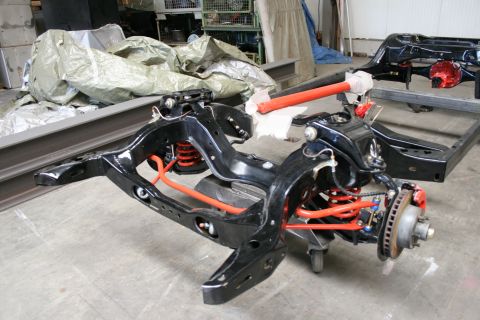 1973 Ford Ranchero - A vehicle's chassis frame, black paint and bright red and orange suspension components, sits in a workshop.