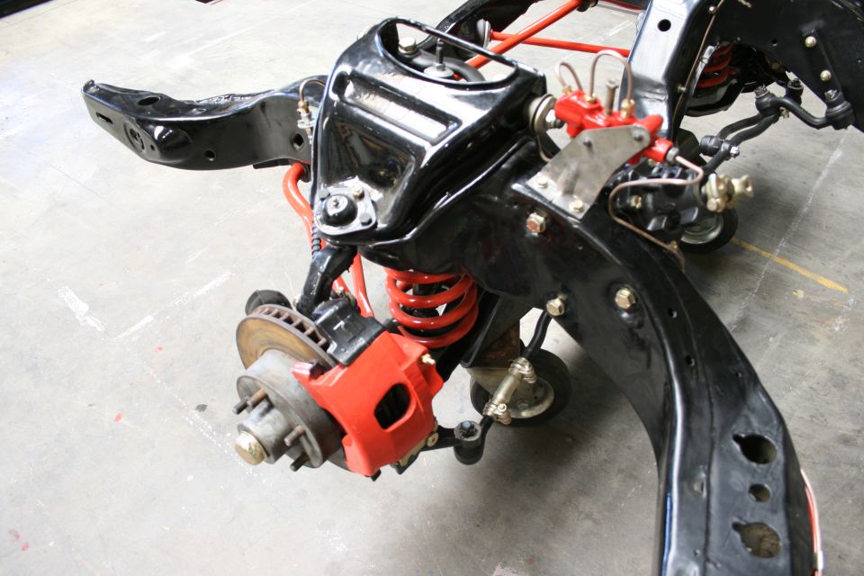Black vehicle frame with red suspension components and disc brake assembly