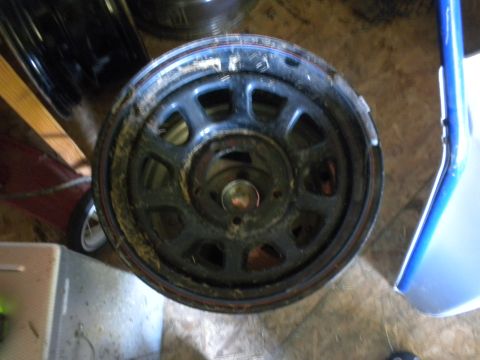 1989 Ford Bronco - A close-up view of a single black steel wheel, showing its multi-spoke design and some dirt accumulation.