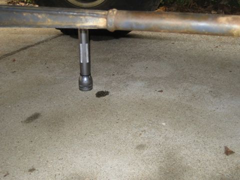 1995 Ford Bronco - A socket wrench is positioned on concrete near oil stains, with a vehicle tire in the background.