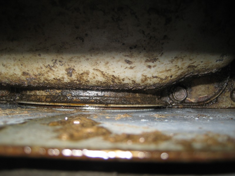 Underside of a vehicle showing a greasy seal and some oil drips