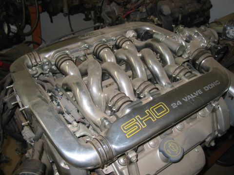 1993 Ford Taurus - Overhead close-up of a Ford SHO V6 engine out of the car, showing the signature polished tubular Yamaha intake manifold runners over the pl…