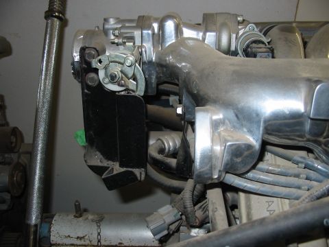 1993 Ford Taurus - Close-up of a polished cast-aluminum intake manifold with long curved runners, showing the throttle body, throttle cam and linkage, and a b…