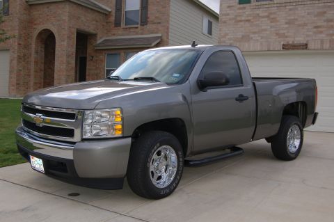 2007 Chevrolet Silverado 1500 - A gray 2007 Chevrolet Silverado 1500 pickup truck is shown from the front three-quarter view in front of a brick house.