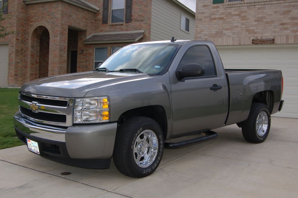 Gray 2007 Chevrolet Silverado 1500 pickup truck with chrome wheels and tinted windows parked in a driveway