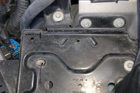 2007 Chevrolet Silverado 1500 - A close-up view of a metal bracket in the engine bay, showing mounting points and some electrical connectors.