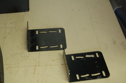 2007 Chevrolet Silverado 1500 - Two black metal L-brackets with slotted holes are shown on a workbench.