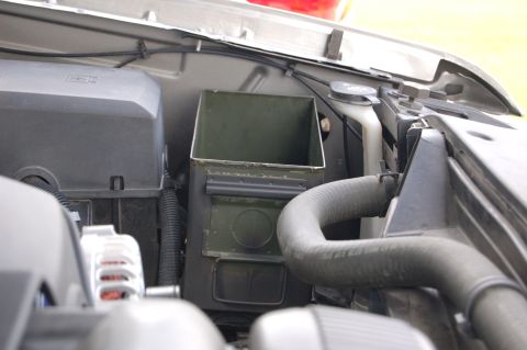 2007 Chevrolet Silverado 1500 - An ammo can is mounted in the engine bay, serving as a makeshift toolbox, positioned near the radiator hose.