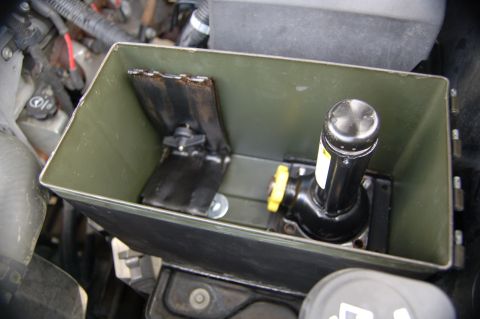 2007 Chevrolet Silverado 1500 - A vehicle jack is secured inside an ammo can, which is mounted in the engine compartment.